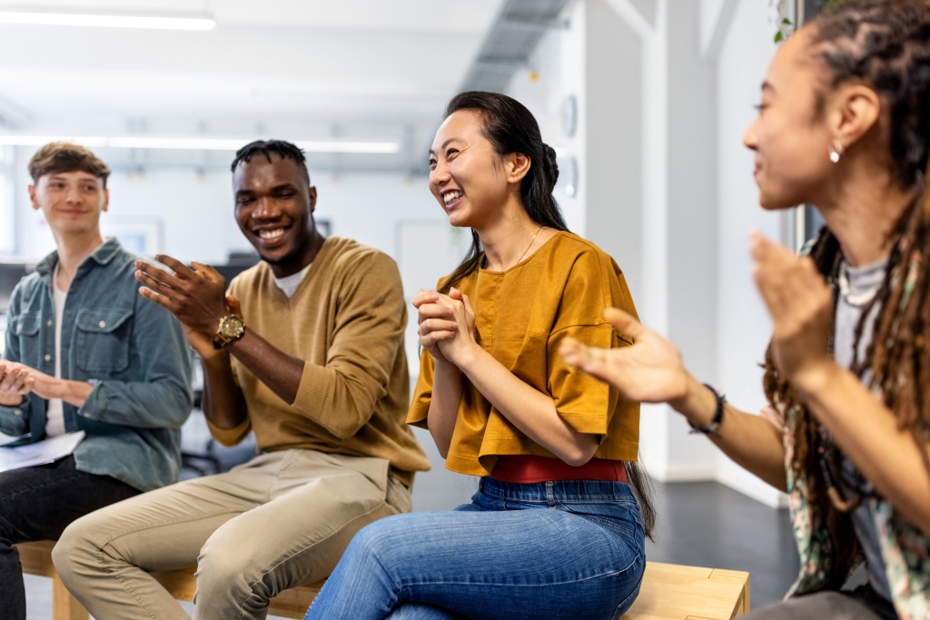 Diverse coworkers sitting together smiling and clapping hands