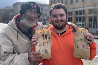 Two people holding sack lunches provided by Blanchet House