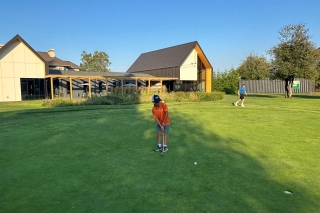 A child putting toward the hole on a putting green