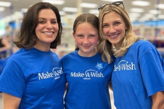 Two adults with a child all smiling and wearing blue Make-A-Wish t-shirts