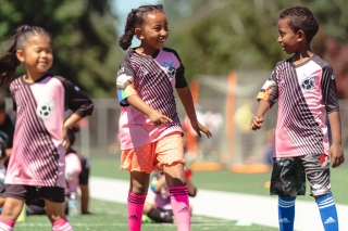 Three kids playing in a soccer game
