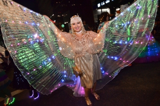 A person at the Portland Rose Festival dressed in an elaborate, sparkling costume with multi-colored, butterfly-like wings