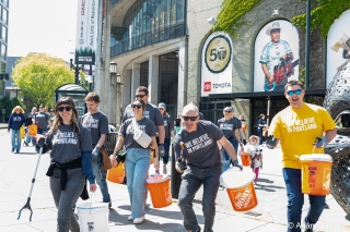 Several AdoptOneBlock volunteers cleaning up outside a soccer stadium