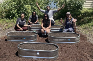 Five people filling metal planter boxes with garden soil