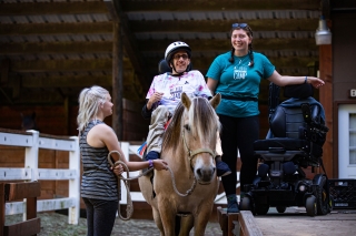 A person with a disability on a horseback ride assisted by two other people