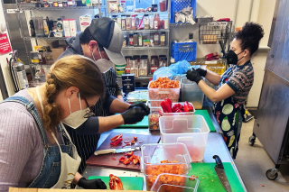 Three people chopping vegetables in a kitchen