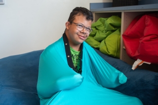 A child with glasses wearing a turquoise-colored wrap