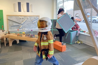 A child wearing an astronaut helmet and a fireman jacket
