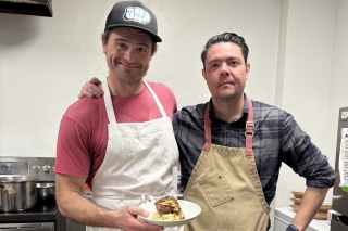 Two people in aprons preparing food in a kitchen