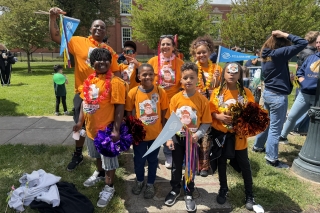Group photo of adults and kids wearing bright orange Dream Big t-shirts