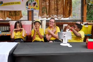 Three kids with an adult with yellow Lemonade Day t-shirts on