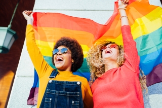Two people holding a rainbow flag