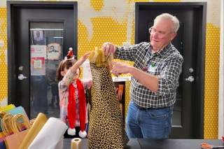 A child and an older man wrapping a gift together