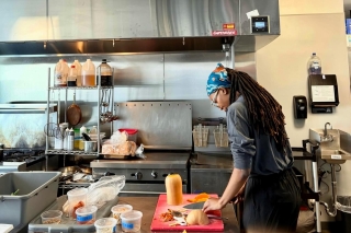 A person in a kitchen peeling and slicing butternut squash