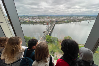 Children looking at overhead view of the Hawthorn Bridge and the Willamette River from inside a building