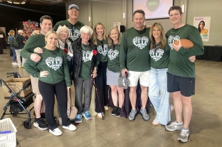 A group photo of people wearing forest green sweatshirts with a white heart-shaped graphic that says, What Would Elle Do