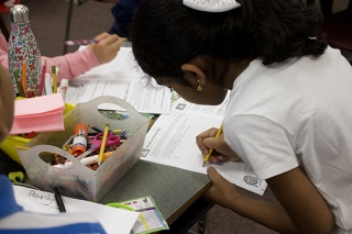 A girl writing on a piece of paper in a classroom