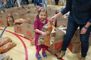 A young girl helping to load bags of potatoes