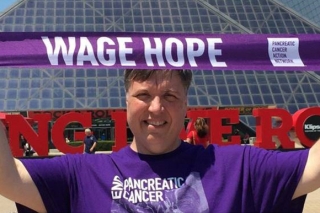 Photo of a man holding a Wage Hope banner