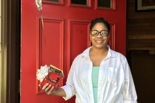 Photo of a woman receiving an appreciation in front of a red door