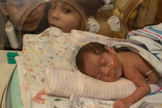 Photo of a baby in the hospital with siblings