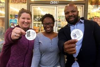 Photo of three people holding up stickers