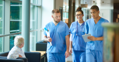 Two male doctors and a female doctor looking at a tablet