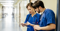 A male and female doctor looking at a tablet