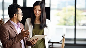 A man with a tablet talking with a woman in an office