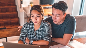 An Asian couple looking at a laptop