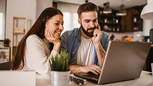 A couple looking at a laptop in their kitchen