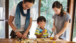 Thumbnail photo of an Asian family slicing vegetables together in a kitchen