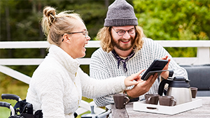 A woman in a wheelchair with a man having coffee at a table